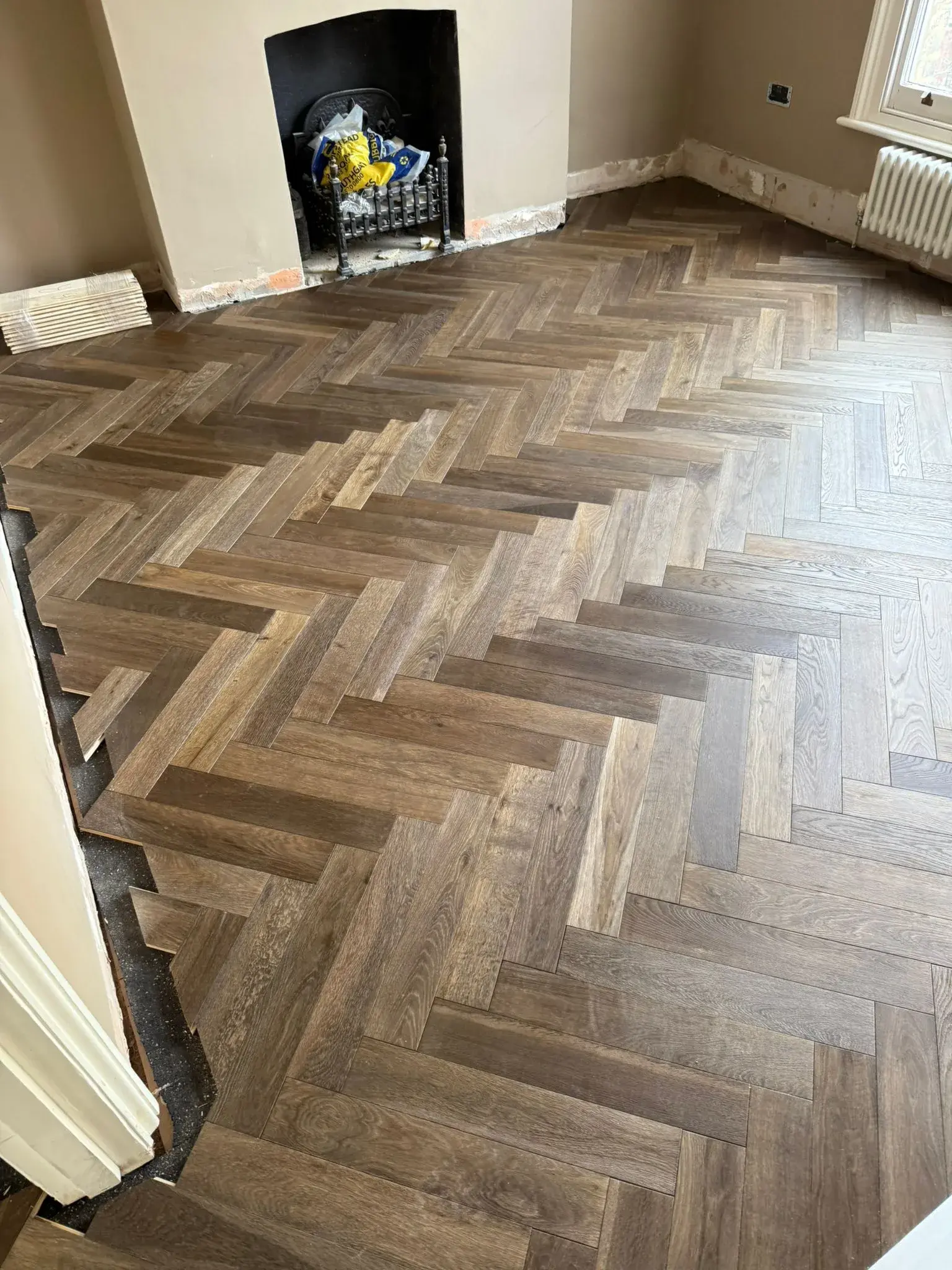 American Oak Herringbone Rich Walnut engineered oak flooring fitted in a reception room, mid-installation, St Albans